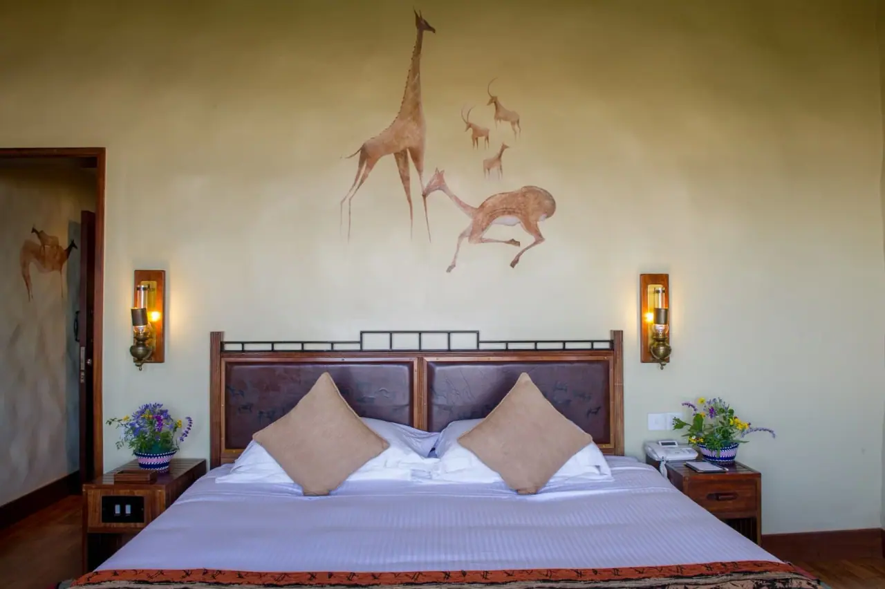 Guest room at Ngorongoro Serena Safari Lodge decorated with rock-art-style wildlife murals