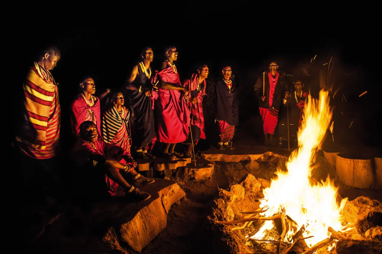 Maasai warriors singing around an evening campfire at Original Maasai Lodge