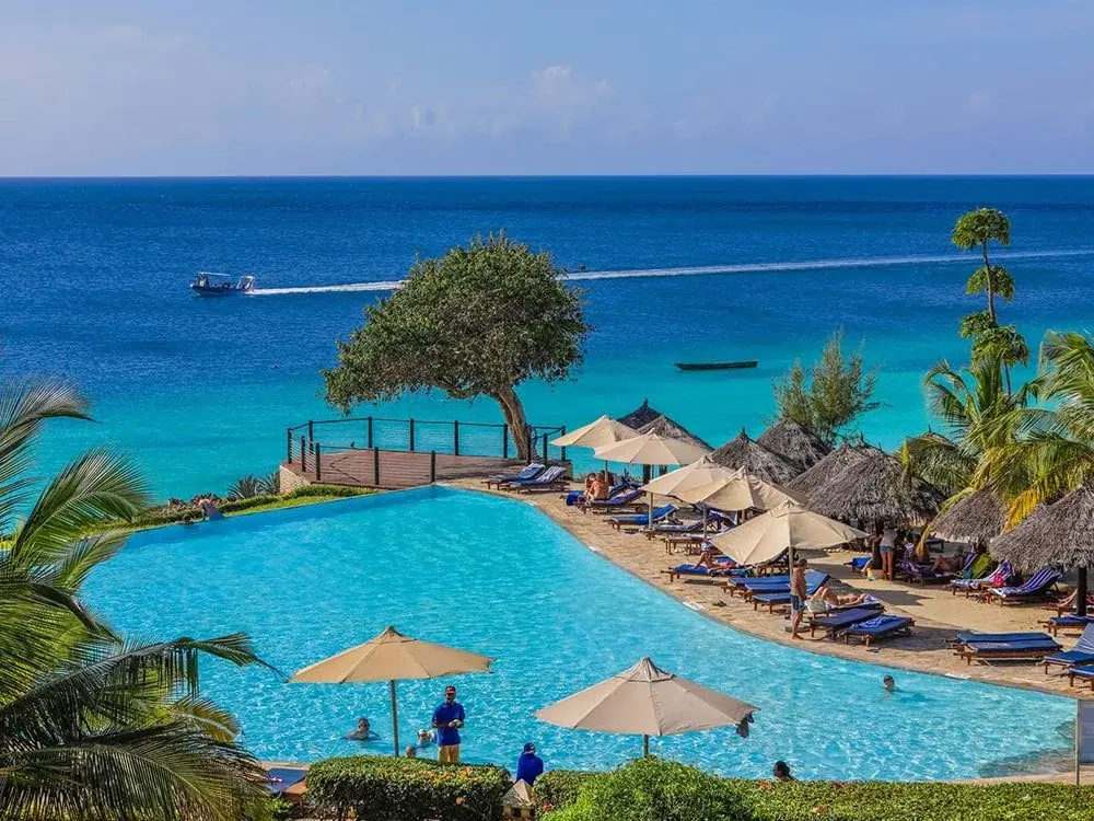 Infinity pool overlooking the Indian Ocean with sun loungers and thatched umbrellas at Royal Zanzibar