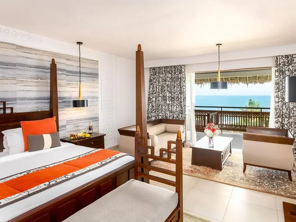 Four-poster suite bedroom with a private ocean-view balcony at Royal Zanzibar