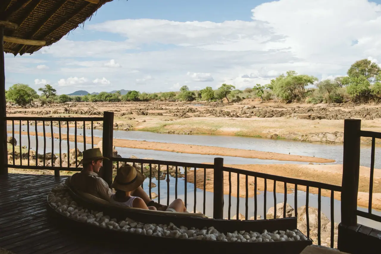 Guests relaxing on a private deck overlooking the rocky Great Ruaha riverbed at Ruaha River Lodge