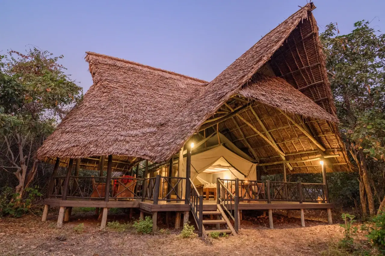 Thatched tented suite exterior at dusk at Rufiji River Camp in Nyerere National Park