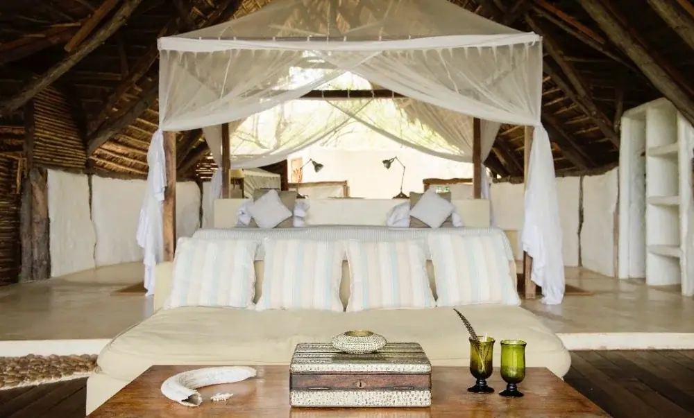 Open-air bedroom with mosquito-net canopy overlooking the bush at Sand Rivers Selous