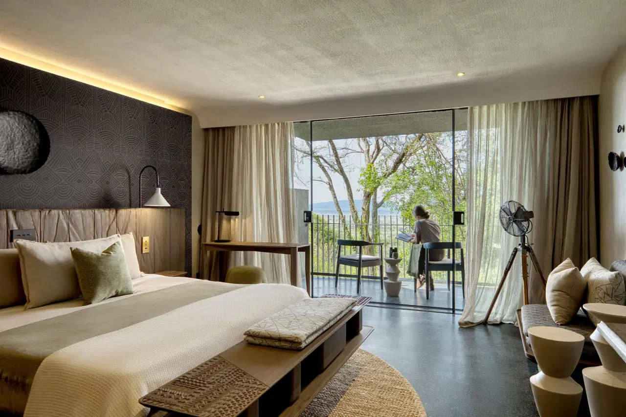 Suite bedroom with a private balcony overlooking the plains at Serengeti Explorer, guest reading outside