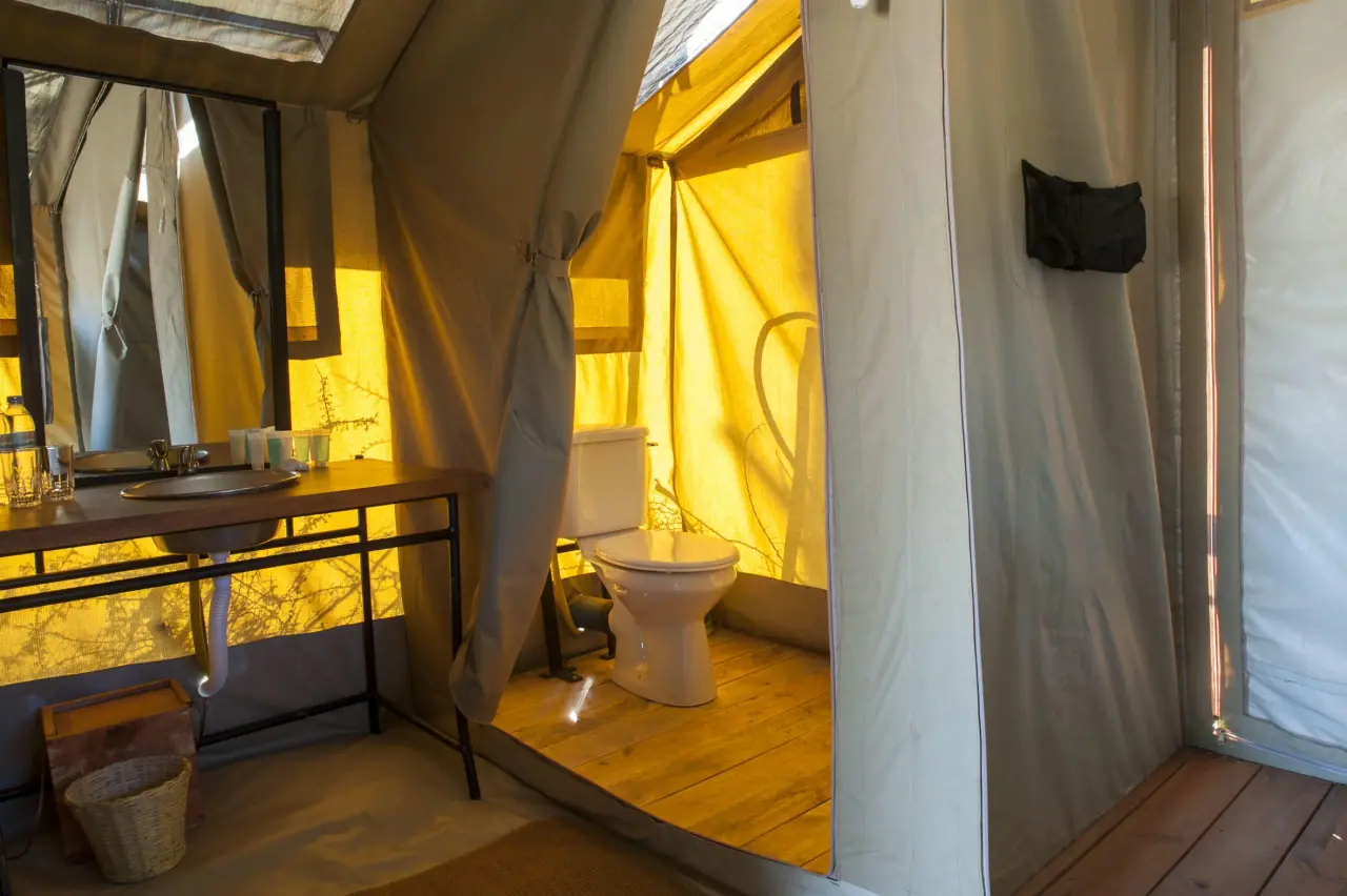 En-suite canvas tent bathroom with sink and toilet at Serengeti Katikati Camp