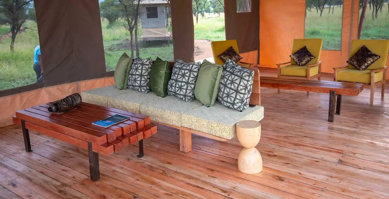 Canvas lounge tent at Serengeti Queens Camp with sofa seating, patterned cushions and views over the plains