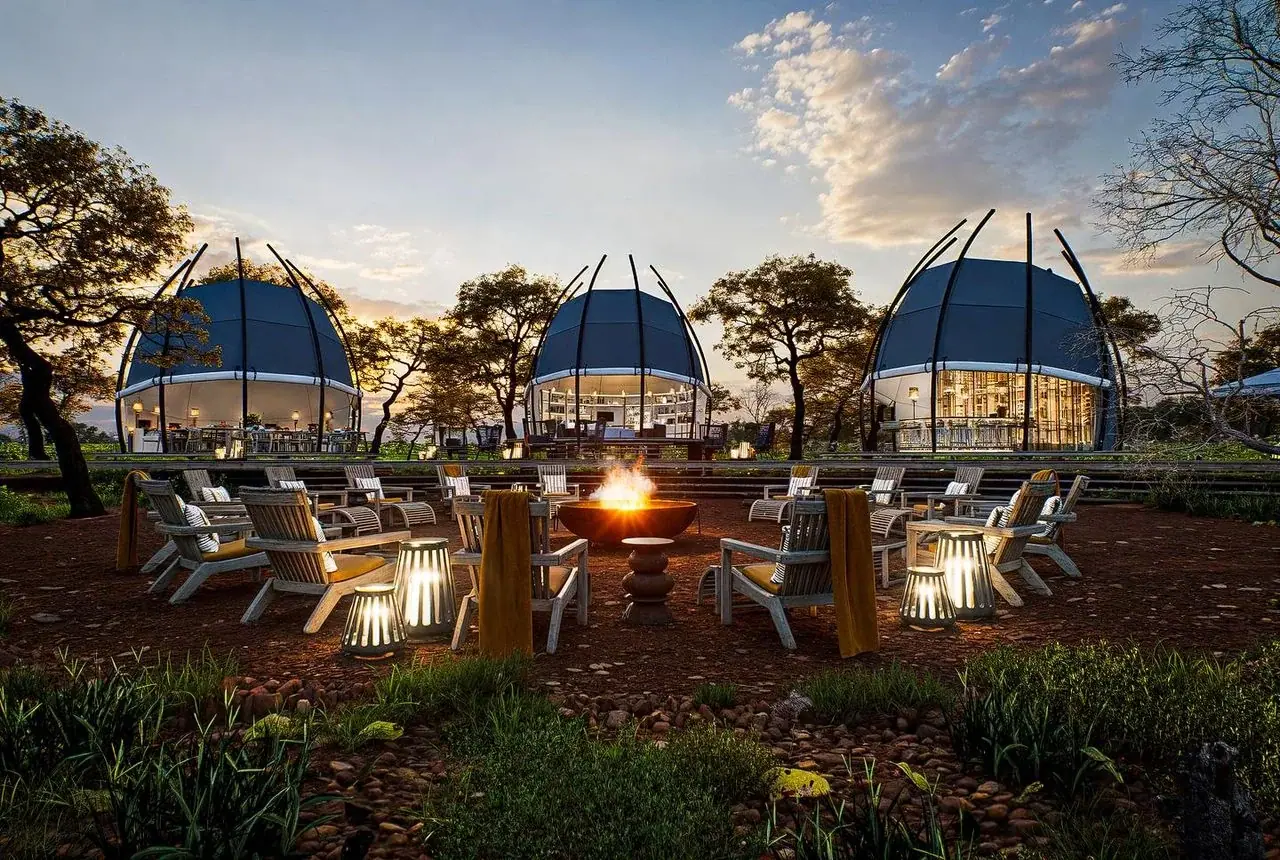 Dome-shaped guest pods at Siringit Tarangire Camp lit up at dusk around an outdoor firepit lounge