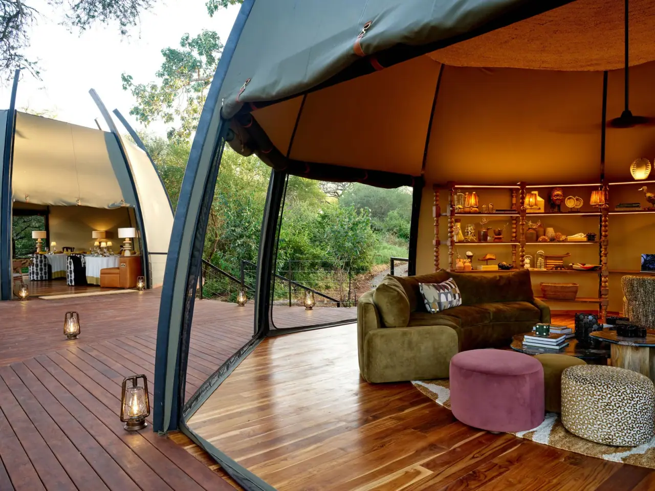 Open-air lounge deck at Siringit Tarangire Camp with a sofa, curated decor shelving and dining area beyond
