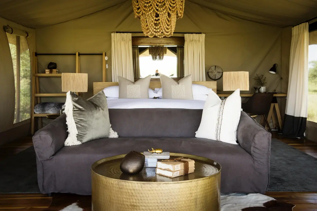 Suite bedroom at Siringiti Serengeti Camp with a beaded chandelier, king bed and sofa seating area