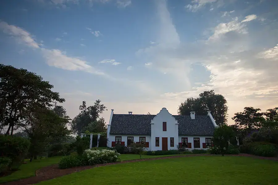 Cape Dutch-style manor house exterior at The Manor at Ngorongoro at dusk with manicured gardens