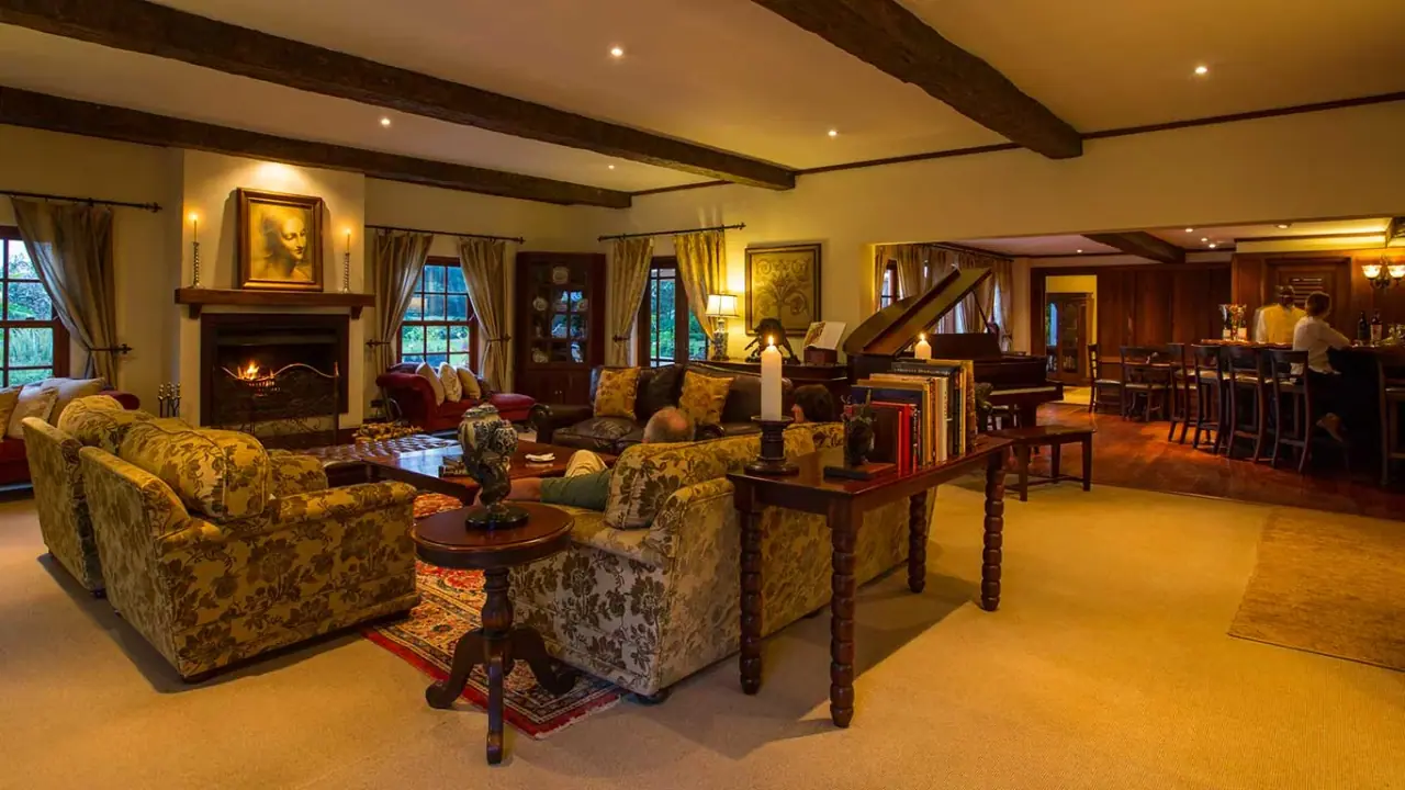 Lounge with a fireplace, grand piano and bar at The Manor at Ngorongoro