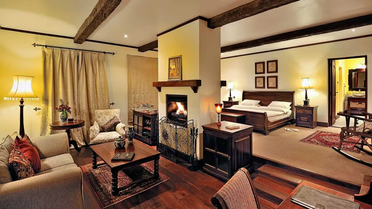 Suite at The Manor at Ngorongoro with a lit fireplace, sitting area and four-poster bed