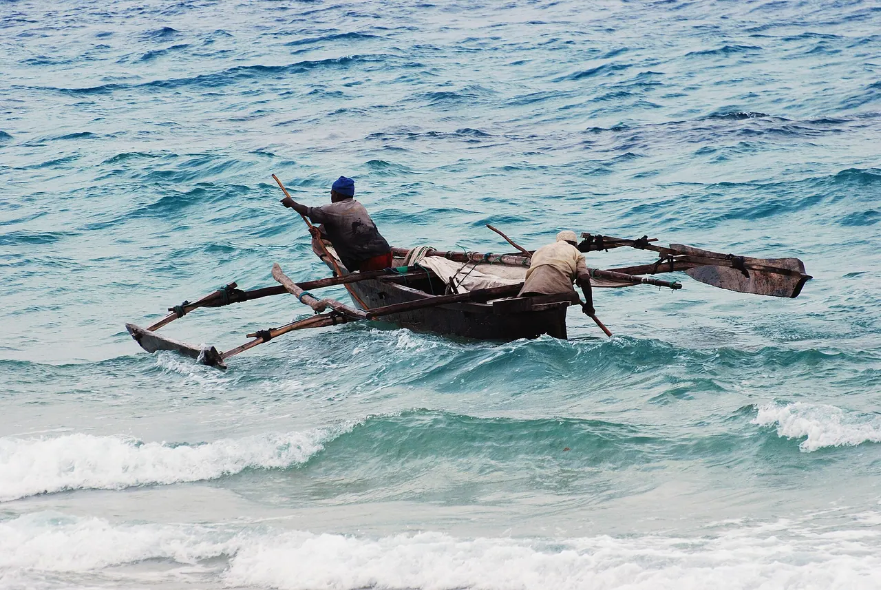 An outrigger canoe riding turquoise waves off the Stone Town shore