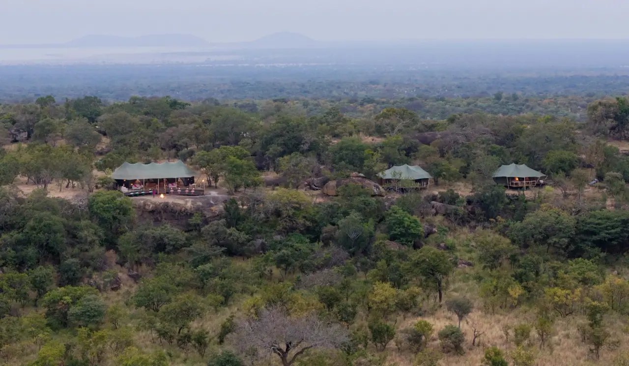 Aerial view of tented camp buildings perched among rocky kopjes and bushveld at Zuri Kilima Siri