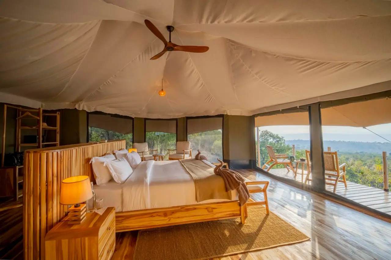 Tented bedroom suite at Zuri Kilima Siri with a wooden bed frame and private deck overlooking the plains
