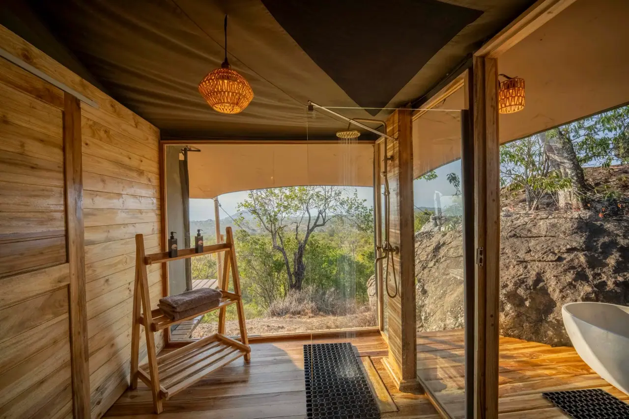 Open-air rain shower and bathroom at Zuri Kilima Siri set against a granite boulder and bush view