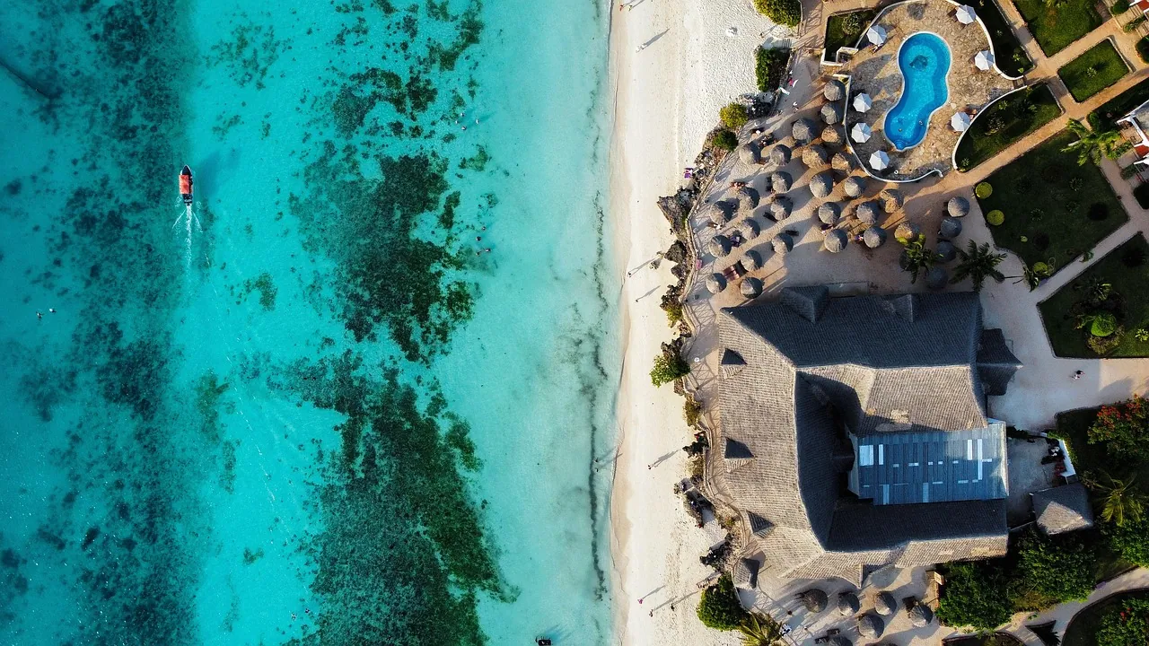 Aerial view of a white-sand beach and turquoise water beside a resort
