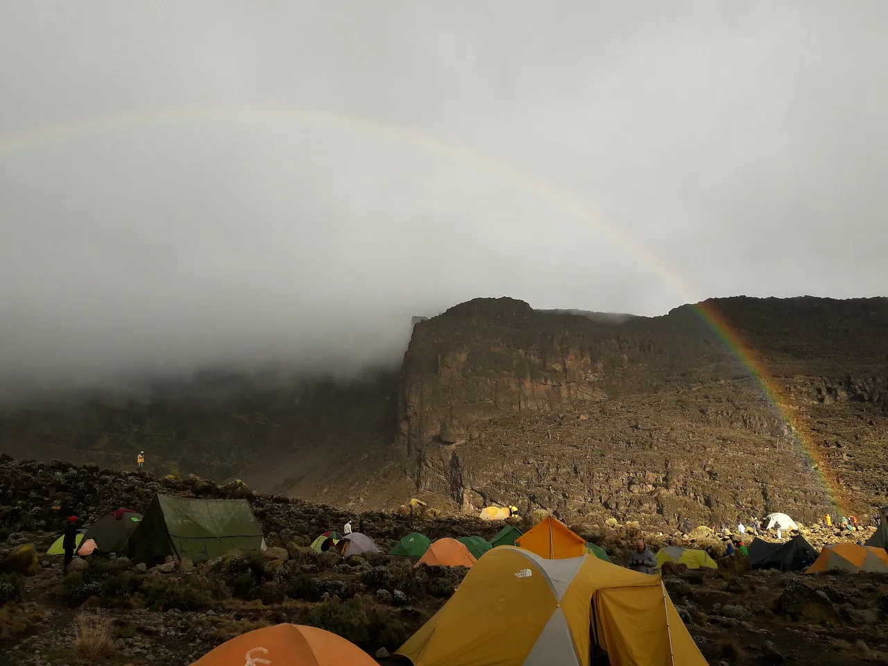 Tents in the misty Barranco valley with a faint rainbow