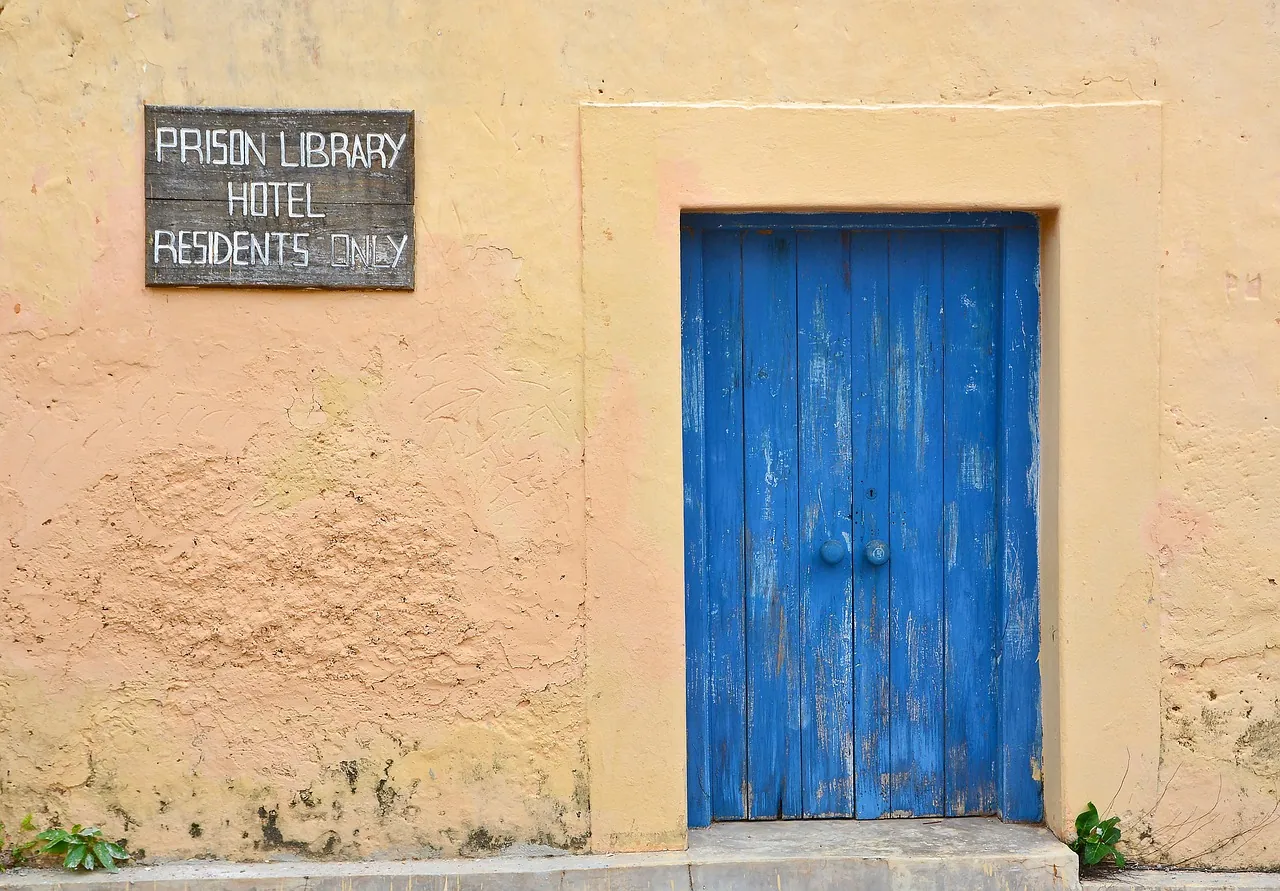 A blue wooden door in a sun-faded peach wall