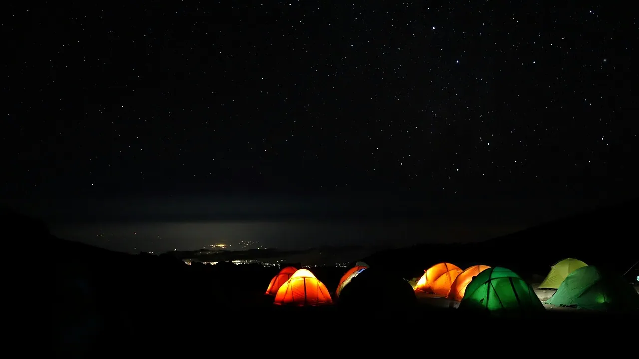 Lit tents glowing in the dark high on the mountain