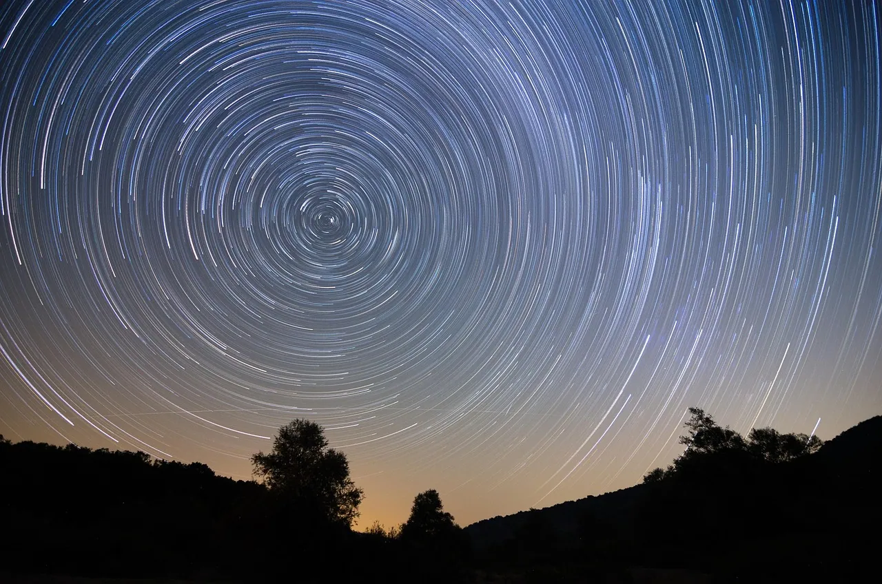 Star trails circling above a dark ridge