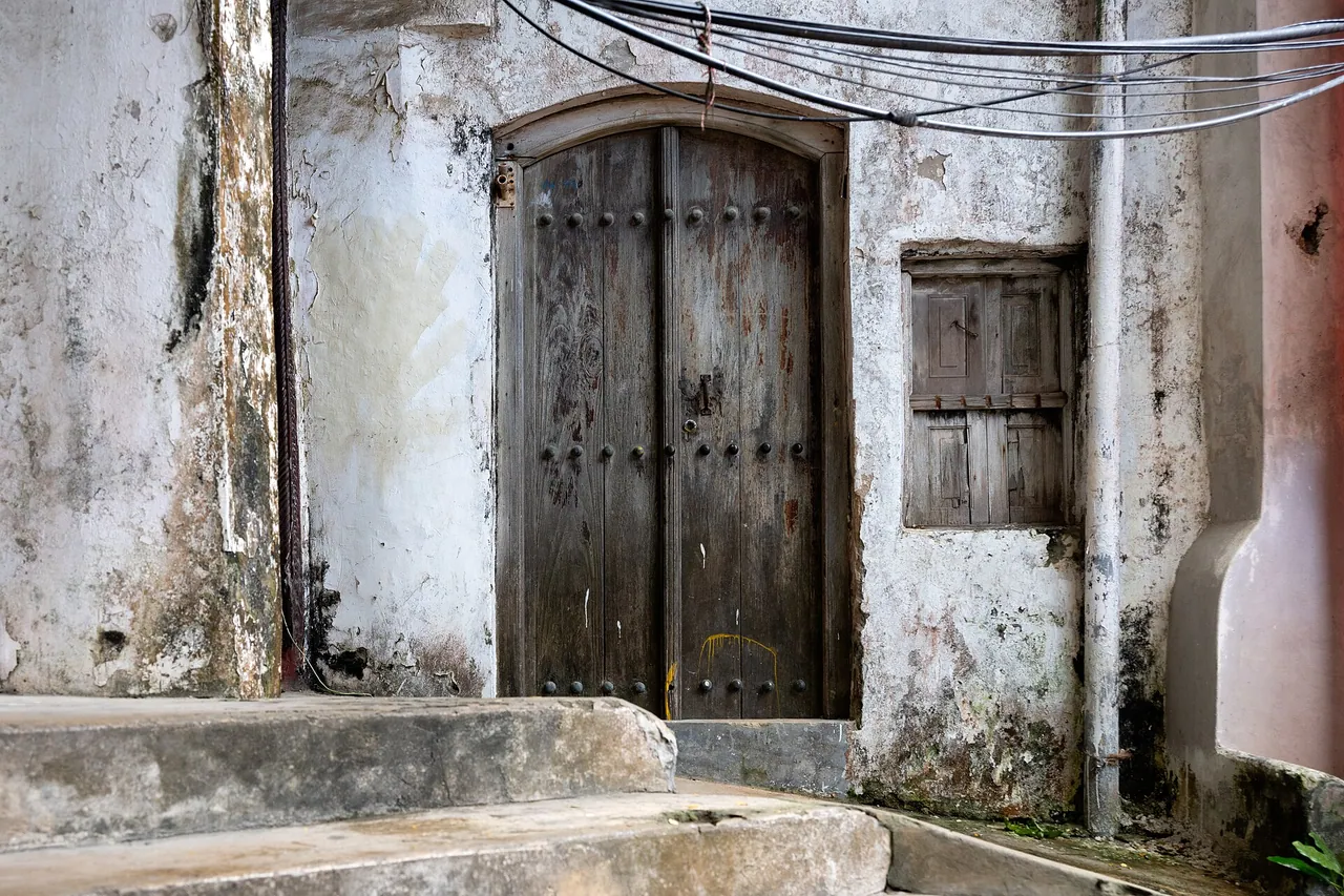 A carved wooden door in a weathered Stone Town building