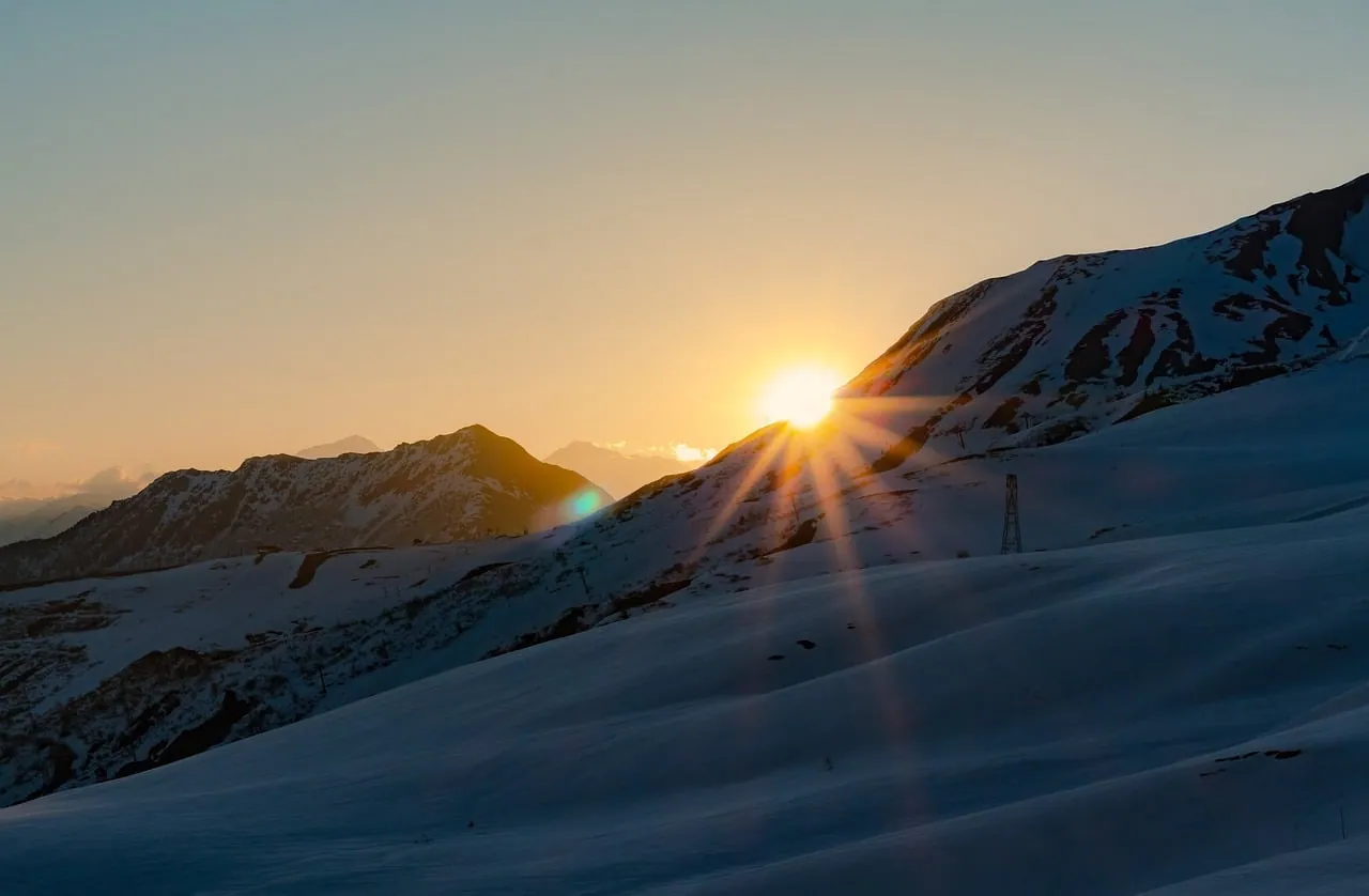 The sun rising over a snowy mountain ridge