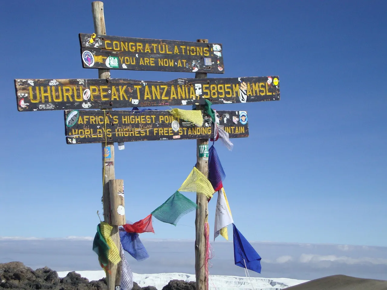The Uhuru Peak sign at the summit of Kilimanjaro, hung with prayer flags