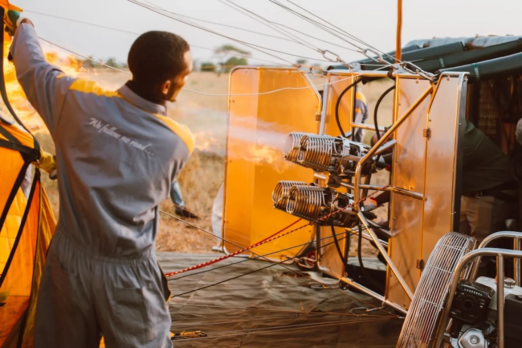A balloon pilot firing the burner while inflating a hot air balloon at dawn